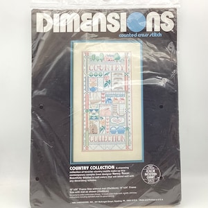 May include: A Dimensions counted cross stitch kit titled "Country Collection." The kit features a sampler with country motifs, including a rabbit, houses, and flowers. The frame size is 10"x20" without a mat, and 14"x24" with a mat.