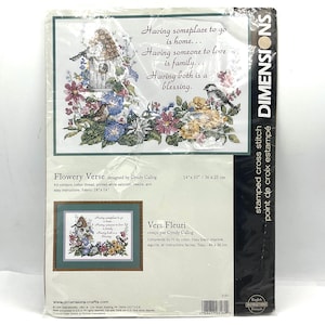 May include: A Dimensions stamped cross stitch kit, titled "Flowery Verse," featuring a floral design with a birdhouse and a bird. The kit includes cotton thread, a needle, and instructions. Fabric size is 18" x 14" (46 x 36 cm).