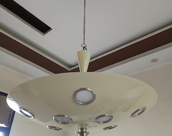 May include: A cream-colored saucer-shaped pendant light fixture suspended by a metal chain. The fixture features multiple circular recessed LED lights with silver-toned rims arranged around the underside, and a central silver-toned metal finial.