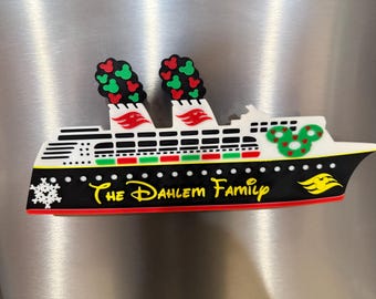 May include: A cruise ship magnet featuring a black hull with the yellow text The Dahlem Family, white upper decks, two smokestacks with red and green mouse-ear patterns, a green wreath with red hearts, and a white snowflake icon.