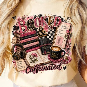 Puede incluir: Una camiseta de color crema con un estampado gráfico que incluye el texto "BOOKED & Caffeinated". El diseño muestra una pila de libros, un diario de lectura, auriculares, un libro abierto con una flor y una taza de café con espuma en forma de corazón.