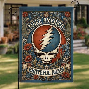 Puede incluir: Una bandera de jardín rectangular con fondo azul presenta el texto "MAKE AMERICA" sobre una calavera con un rayo y el texto "GRATEFUL AGAIN". La bandera tiene un borde decorativo con flores y pavos reales.
