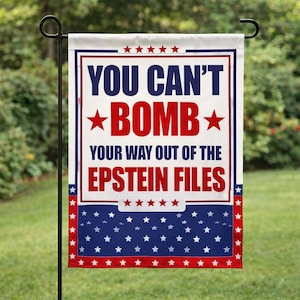 May include: A white garden flag with the text "YOU CAN'T BOMB BOMB YOUR WAY OUT OF THE EPSTEIN FILES" in blue and red. The flag has a blue and white star pattern at the bottom and red stars at the top.