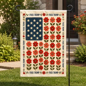 May include: A garden flag with a floral design incorporating the American flag. The flag features a blue square with white stars and red flowers. The text "FUCK TRUMP" is repeated around the edges.