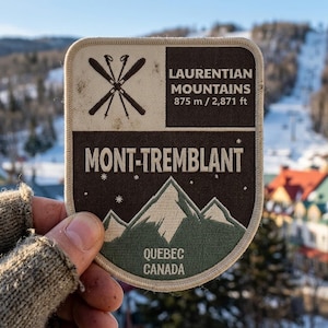 May include: A rectangular patch featuring a ski design and the text "MONT-TREMBLANT". The patch also includes the text "LAURENTIAN MOUNTAINS 875 m / 2,871 ft" and "QUEBEC CANADA". The patch has a brown, beige, and green color scheme.