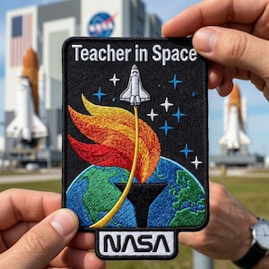May include: A black patch with the text "Teacher in Space" and a NASA logo. The patch features a white space shuttle launching from Earth, with flames in red, orange, and yellow. Blue stars are scattered across the black background.