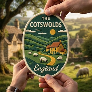 May include: An oval embroidered patch featuring a landscape of The Cotswolds, England. The design shows a yellow house, a winding path, and sheep on green hills under a yellow sun. The text reads THE COTSWOLDS at the top and England at the bottom.