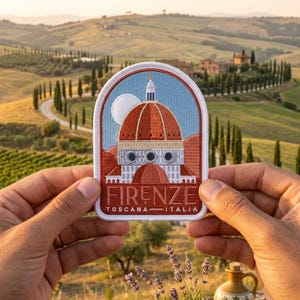 May include: An embroidered patch featuring a depiction of the Florence Cathedral dome in terracotta and white against a light blue sky. The text FIRENZE TOSCANA ITALIA is stitched in white at the bottom of the arched, white-bordered patch.