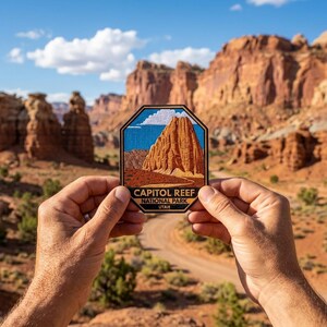 May include: A patch featuring a landscape of Capitol Reef National Park in Utah. The patch has a blue border and displays a rock formation under a blue sky with white clouds. The text "CAPITOL REEF NATIONAL PARK UTAH" is printed on the bottom.