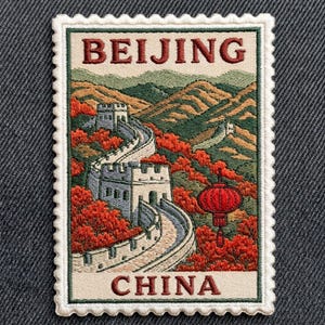 May include: A rectangular embroidered patch with a scalloped border featuring a landscape of the Great Wall of China winding through mountains with red autumn trees and a red lantern. The text BEIJING is at the top and CHINA is at the bottom.