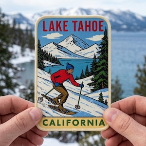 May include: A rectangular embroidered patch featuring the text LAKE TAHOE at the top and CALIFORNIA at the bottom. The design depicts a person in a red sweater and blue beanie snowshoeing through a snowy landscape with mountains and pine trees.