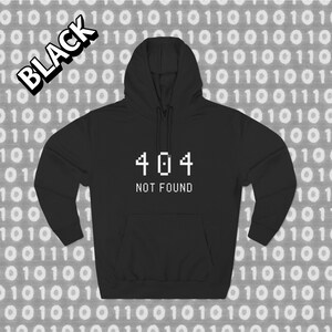 Peut inclure: Sweat à capuche noir avec le texte "404 NOT FOUND" en blanc, un message d'erreur courant en informatique. Le mot "BLACK" est imprimé en blanc, souligné de noir, en haut à gauche. Le fond est un motif de code binaire.