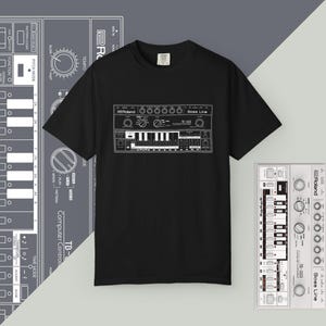 Op de afbeelding: Zwart t-shirt met een witte afbeelding van een Roland TB-303 synthesizer. Het ontwerp bevat het Roland-logo, knoppen, toetsen en de woorden "Bass Line" en "TB-303". Extra synthesizerdiagrammen staan op de achtergrond.