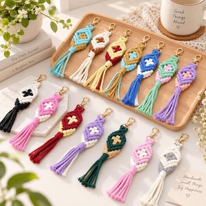 Puede incluir: Una colección de llaveros de macramé con patrones tejidos en forma de diamante y borlas largas. Cada llavero está hecho de cordón de algodón en varios colores, incluyendo azul, rosa, rojo, morado, verde y blanco, con un cierre de metal dorado.