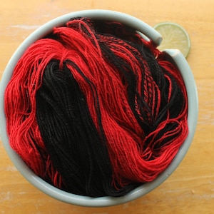 Puede incluir: Un bol de hilo rojo y negro.