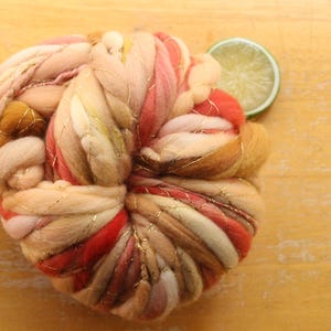 May include: A ball of yarn with pink, white, red, and gold threads. The yarn is arranged in a circular shape, with the gold threads running through the center.