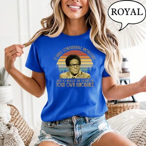 May include: Royal blue t-shirt featuring a vintage-style graphic of a man in glasses with the quote, "It takes considerable knowledge just to realize the extent of your own ignorance."