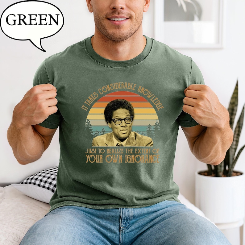 May include: Green t-shirt featuring a portrait of a man wearing glasses, set against a sunset design. The shirt includes the quote, "It takes considerable knowledge just to realize the extent of your own ignorance."