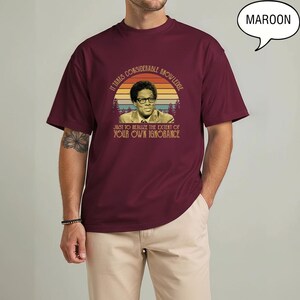 May include: Maroon t-shirt featuring a vintage-style graphic with a portrait and the quote: "It takes considerable knowledge just to realize the extent of your own ignorance."