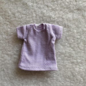 Puede incluir: Una peque&ntilde;a camiseta de color lavanda con mangas cortas. La camiseta est&aacute; hecha de una tela de punto suave y tiene un escote redondo simple. El dobladillo y las mangas est&aacute;n cuidadosamente cosidos.