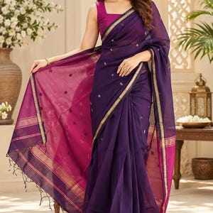May include: A deep purple saree featuring a magenta inner border and gold metallic trim. The fabric is sheer with small embroidered floral motifs scattered throughout. It is paired with a sleeveless magenta blouse with a square neckline.