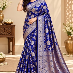 May include: A vibrant royal blue saree featuring an intricate gold floral brocade pattern throughout the fabric. The garment includes a wide, ornate gold border with geometric and botanical motifs, draped elegantly to showcase the detailed weave.