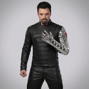 Op de afbeelding: Een persoon draagt een zwarte leren jas en broek, met een metalen zilveren arm en hand. De zilveren arm heeft een rood sterembleem op de schouder. De jas heeft een geribbeld ontwerp.