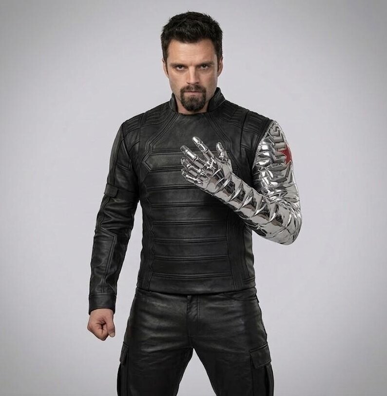 Op de afbeelding: Een persoon draagt een zwarte leren jas en broek, met een metalen zilveren arm en hand. De zilveren arm heeft een rood sterembleem op de schouder. De jas heeft een geribbeld ontwerp.
