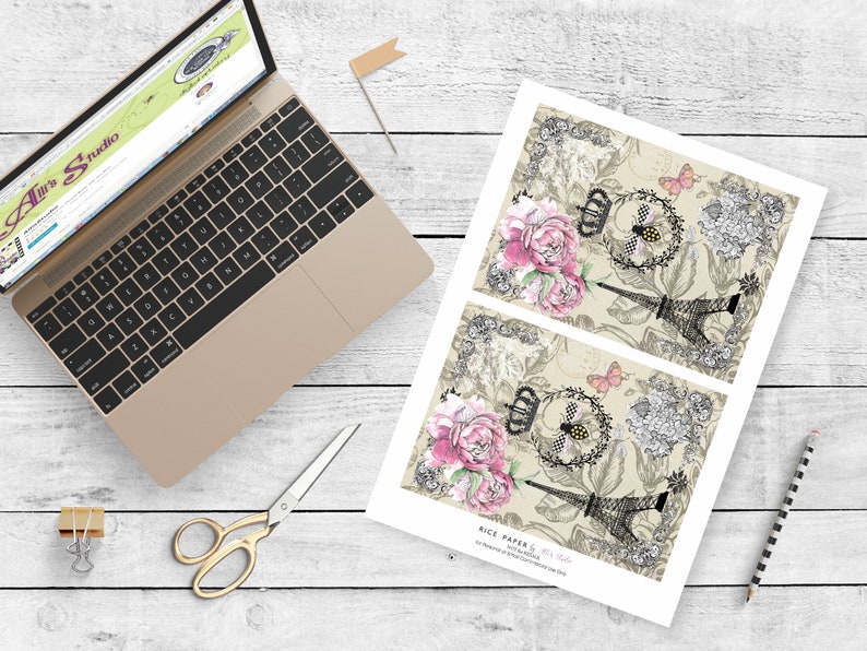 May include: Two sheets of decorative rice paper with a vintage Parisian theme. The paper features a black and white illustration of the Eiffel Tower, pink and white flowers, a bee, and a butterfly. The text "Rice Paper &  Jet-Set Style" is printed at the bottom of the sheet.