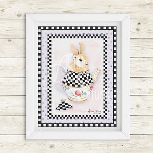 May include: A framed watercolor print featuring a rabbit inside a teapot. The rabbit wears a checkered collar and a flower. The teapot has floral and gold accents. The print is surrounded by a black and white checkered border and a light purple polka dot border.