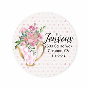 May include: A pink and white checkered teapot with a bouquet of pink roses on a white background with pink polka dots. The text "THE Jensens 2300 Carlito Way Carlsbad, CA 92009" is printed on the label.