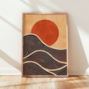 May include: A rectangular wall art print in a wooden frame featuring a graphic illustration of a large, solid burnt orange sun positioned above stylized, dark blue ocean waves composed of repeating, thin, curved line patterns on a tan background.