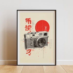 May include: Framed art print featuring a detailed illustration of a vintage camera with the word "FUJI" on the camera body. The artwork includes Japanese characters and a red sun graphic. The print is set against a cream background.