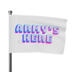 Puede incluir: Una bandera blanca con el texto "ARMY'S HERE" en efecto 3D, utilizando colores azul, morado y rosa. La bandera está sujeta a un mástil plateado y ondea suavemente.