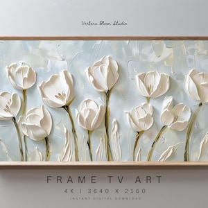 May include: A framed artwork featuring textured white tulip flowers against a light blue background. The wooden frame surrounds the floral design, with the text "Verbena Bloom Studio" at the top and "FRAME TV ART" at the bottom.