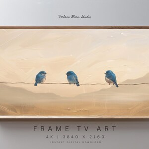 Op de afbeelding: Een ingelijste digitale kunstprint met drie blauwe vogels op een draad tegen een beige landschap. Het kunstwerk heeft een geschilderde textuur, met de tekst "Verbena Bloom Studio" bovenaan en "FRAME TV ART" onderaan. Afmetingen: 3840 x 2160 pixels.