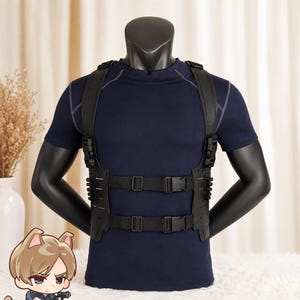 以下が含まれることがあります： 黒いタクティカルチェストハーネス。調節可能なナイロンストラップ、サイドリリースプラスチックバックル、レーザーカットされたMOLLEパネルを備え、黒いマネキンの胴体にダークネイビーブルーの半袖アスレチックシャツの上から着用されています。