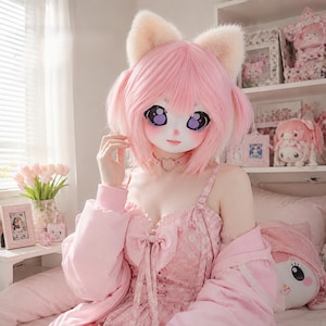 May include: A full-head mask featuring light pink hair, large purple eyes, and fuzzy cream-colored cat ears. The mask is paired with a pink choker featuring a heart-shaped charm, worn with a pink dress and a matching pink jacket over the shoulders.