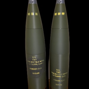 May include: Two olive green projectiles with black tips and copper bands. Each projectile has the text "155 TNT PROJECTILE M795 W/SUPPL CHG" and other markings. The background is black.