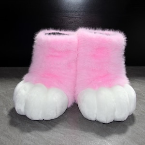 May include: A pair of pink and white furry boots, resembling animal paws. The boots are a vibrant pink color with white paw pads. The boots are designed to be worn on the feet.