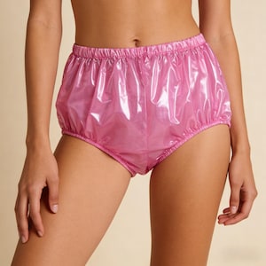 May include: Pink, shiny, high-waisted underwear with an elastic waistband and leg openings. The material has a crinkled appearance, reflecting light. The garment is designed with a gathered, voluminous shape.
