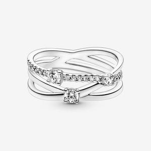 May include: A silver-toned ring set featuring three intertwined bands. The top band is adorned with small, sparkling stones, while the other two bands have a smooth, polished finish. Three larger, clear stones are set at intervals.