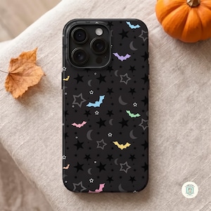May include: A black smartphone case featuring a repeating pattern of dark stars, crescent moons, and small bats in pastel colors including light blue, mint green, yellow, and pink. The case has a cutout for a triple-lens camera system on the back.