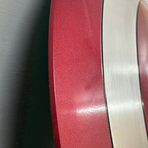 May include: A circular shield featuring alternating concentric rings of metallic red and brushed silver. The surface displays a smooth, reflective finish with a distinct color contrast between the deep red sections and the bright silver bands.