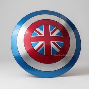 Op de afbeelding: Een rond schild met een blauwe buitenring, een zilveren middenring en een rode binnenring. Het midden toont een Union Jack-ontwerp in rood, wit en blauw. Het schild heeft een glanzende afwerking.