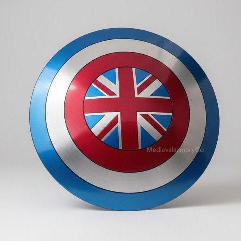Op de afbeelding: Een rond schild met een blauwe buitenring, een zilveren middenring en een rode binnenring. Het midden toont een Union Jack-ontwerp in rood, wit en blauw. Het schild heeft een glanzende afwerking.