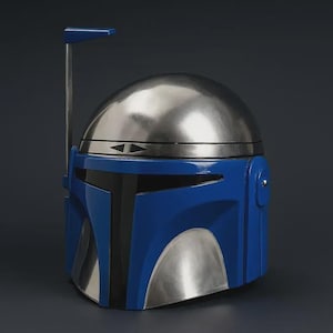 May include: A blue and silver Mandalorian helmet. The helmet features a rounded silver top, a blue faceplate, and a silver lower section. A vertical antenna extends from the top. The helmet is a replica from the Star Wars franchise.