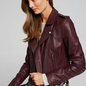 Pu&ograve; includere: Giacca da motociclista in pelle bordeaux con colletto a revers e zip asimmetrica. La giacca ha una piccola tasca con zip e una vestibilit&agrave; aderente. Le maniche sono lunghe. Il colore &egrave; un bordeaux intenso e ricco, in pelle di alta qualit&agrave;.