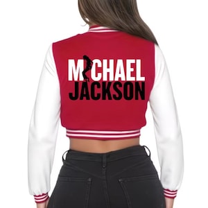 May include: Red and white cropped varsity jacket with the name "MICHAEL JACKSON" in bold white and black letters. A silhouette of a dancer is above the name. The jacket has white sleeves and red trim.