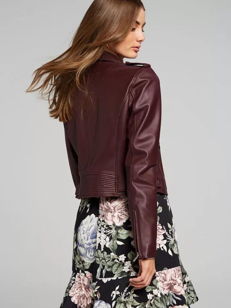 Pu&ograve; includere: Giacca in similpelle bordeaux in stile biker, con colletto a revers, zip asimmetrica e dettagli trapuntati sulle spalle. La giacca &egrave; abbinata a una gonna nera con stampa floreale.